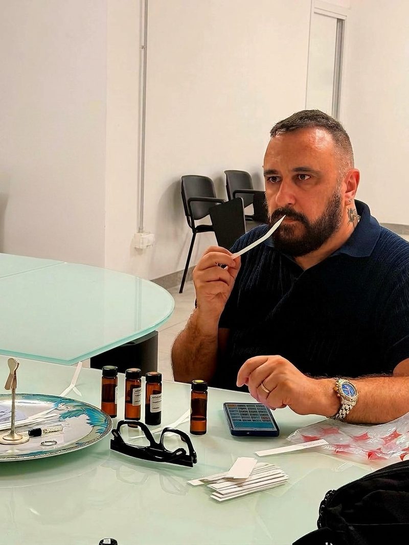 Pierangelo Dal Ben annusa una striscia profumata durante il corso di formulazione, con le boccette davanti